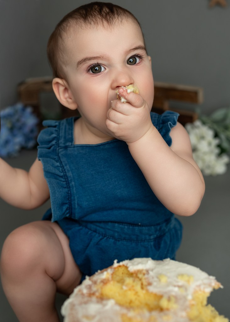 Adorable toddler enjoying a fun-filled cake smash session, covered in colorful frosting with a big smile. A messy, sweet celebration captured in a joyful moment!
